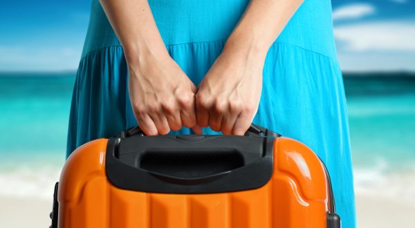 woman's hands holding orange suitcase